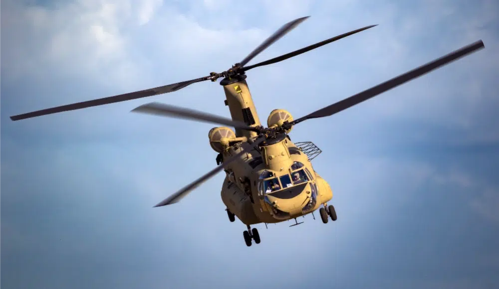 A military helicopter flying in a blue sky.